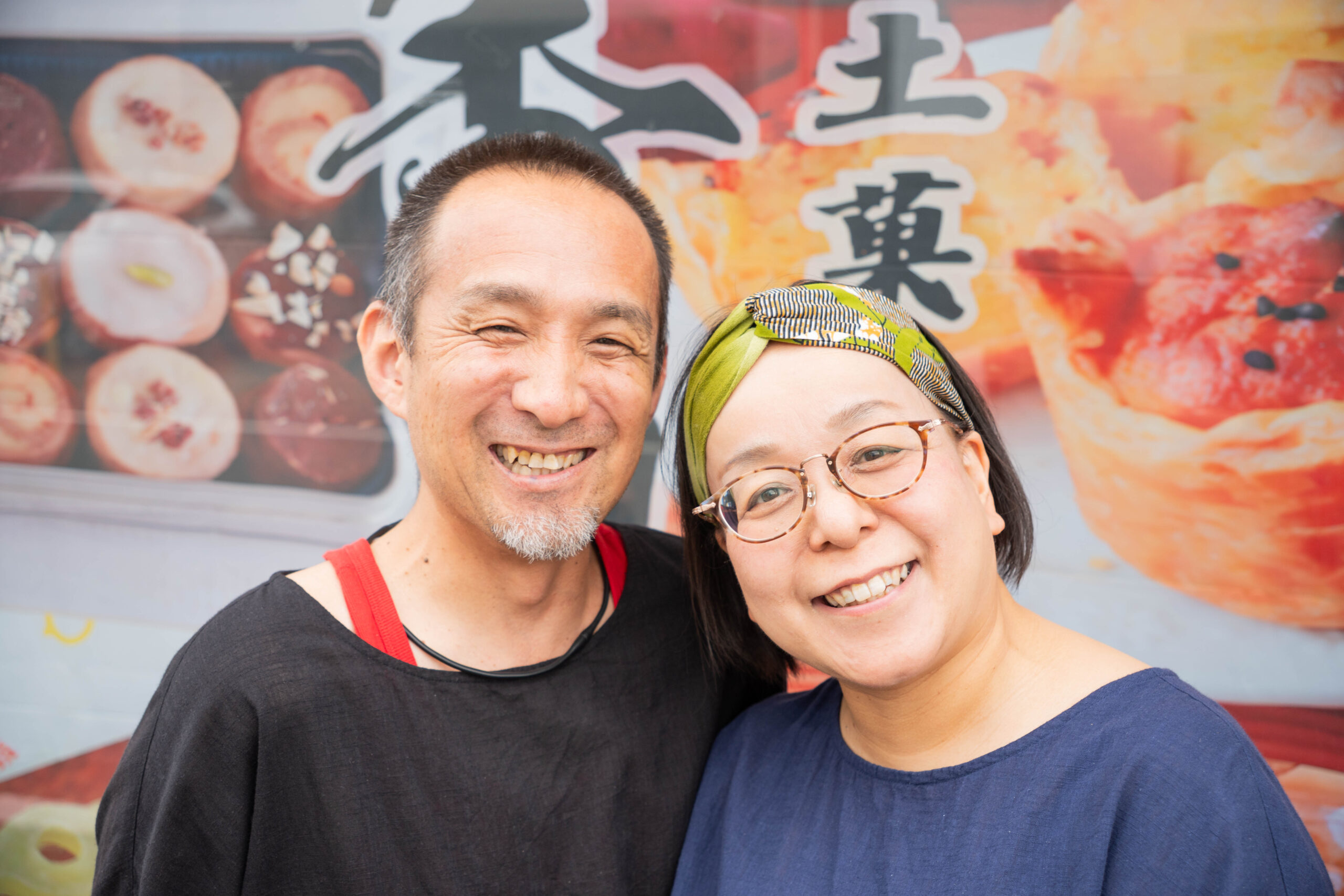 「DESIGN STUDIO FUUによる店舗出張撮影。和菓子店のお店の前で仲良く寄り添い微笑む男女のポートレート」