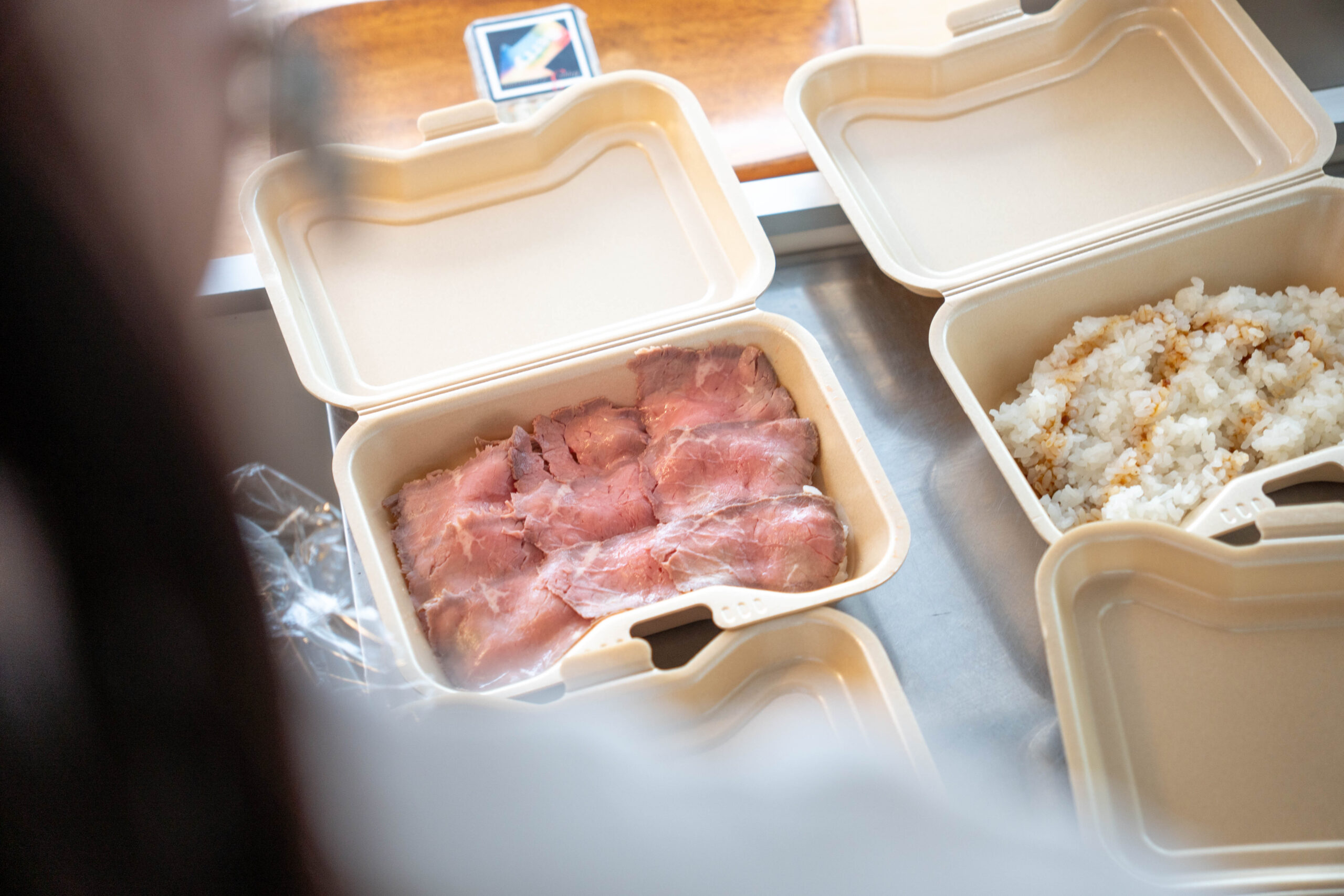 キッチンカーBerryでローストビーフ丼の肉を容器に盛り付けている調理風景